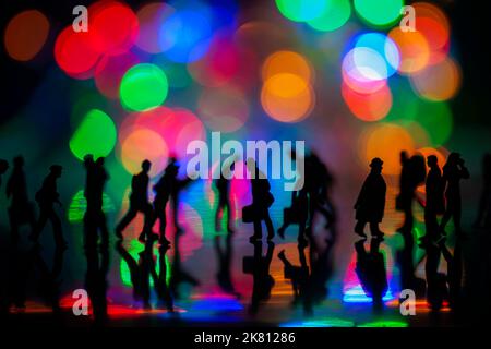 Miniature people toys studio set up - Silhouette side view of people busy walking with colorful blurred bokeh background. Focus at the man in the midd Stock Photo
