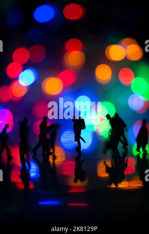 Miniature people toys studio set up - Silhouette side view of people busy walking with colorful blurred bokeh background. Focus at the man in the midd Stock Photo