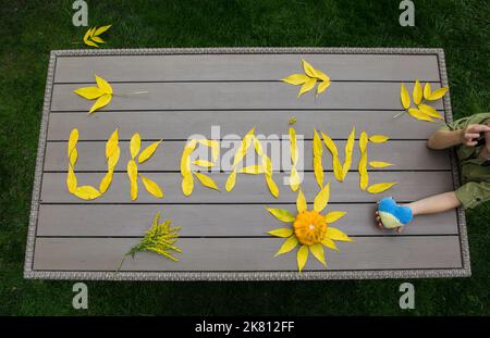 word Ukraine laid out on table of fallen yellow autumn leaves. Ukrainians want peace. Stop war. concept of supporting Ukrainian people, drawing attent Stock Photo