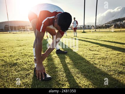 Football, athlete and man doing a stretching exercise for legs on a sport field before a match. Sports, fitness and healthy guy doing a warm up Stock Photo