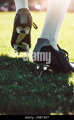 Soccer shoes, soccer player and soccer field by man for training, exercise and sports game. Football field, feet and football player shoe closeup with Stock Photo