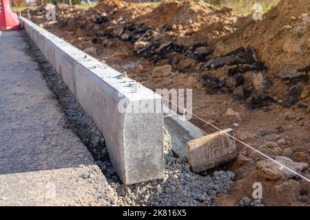 Concrete curbs installation works at road construction site. String line level guide. Stock Photo