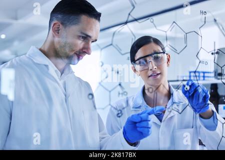 Theyll figure this code out together. two young scientists working on a glass wipe board in their lab. Stock Photo