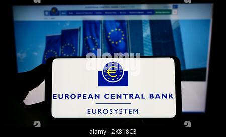 Person holding smartphone with logo of EU institution European Central Bank (ECB) on screen in front of website. Focus on phone display. Stock Photo