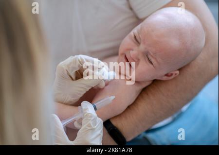 Pediatric doctor injecting the vaccine to the newborn Stock Photo
