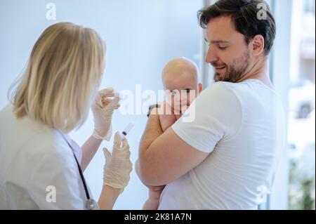 Pediatrician preparing to administer an injection to a newborn Stock Photo