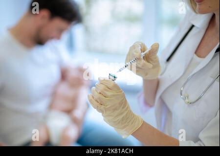 Doctor preparing to administer an injection to a patient Stock Photo