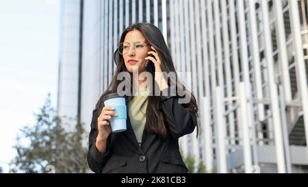 Latin business woman with glasses talking on the cell phone in a business area. Stock Photo