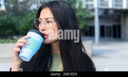 Attractive Latin business woman drinking from her cup of coffee during a break in an office area Stock Photo