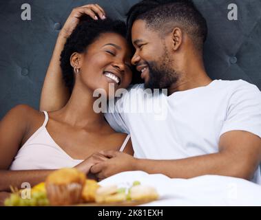 Breakfast together make Sundays even better. a happy young couple enjoying breakfast in bed together at home. Stock Photo