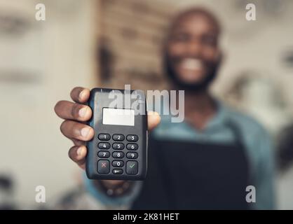Come on, buy the bike. an unrecognizable man standing in his bicycle shop and holding a card machine. Stock Photo