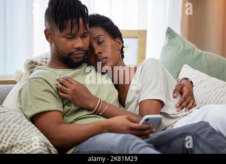 Weekends are for relaxing. a young man using a smartphone while embracing his partner at home. Stock Photo
