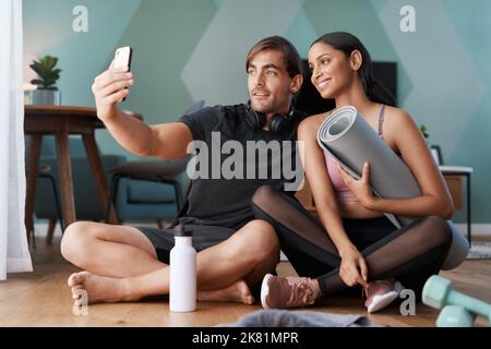Smile babe. Full length shot of an athletic young couple taking selfies after their workout at home. Stock Photo