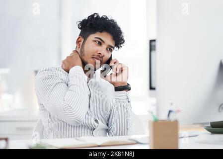 I will have to fix this mess myself. a young businessman looking stressed out while talking on a cellphone in an office. Stock Photo