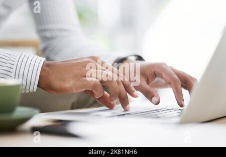 Formulating some emails to his clients. Closeup shot of an unrecognisable businessman using a laptop in an office. Stock Photo