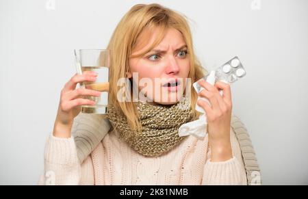 Headache and flu remedies. Get rid of flu. Woman wear warm scarf because illness or flu. Girl hold glass water tablets and thermometer nasal drops Stock Photo