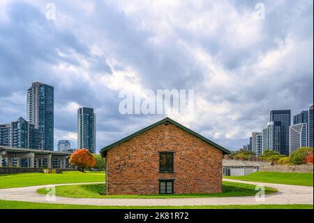 A colonial brick walls building exterior in a overcast weather day. Modern skyscrapers contrast with the antique construction.  Fort York is a Nationa Stock Photo