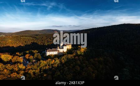 Lockenhaus, Austria - 7 October, 2022: panorama of Lockenhaus Castle surrounded by autumn forest in warm evening light Stock Photo