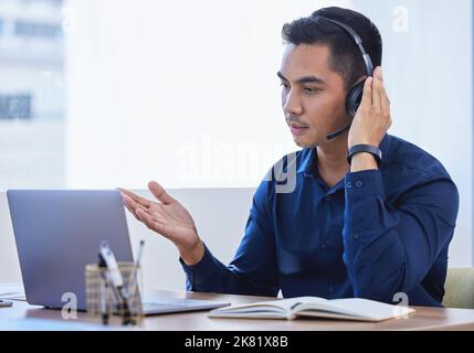 Telecommunication can improve collaboration between people. a young businessman wearing a headset while using a laptop in an office. Stock Photo