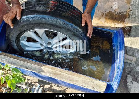 Worker submerge tyre into water container for bubble to check point of punctured Stock Photo