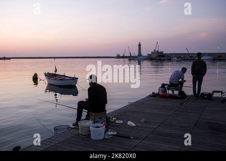 Italy, region of Apulia: Molfetta. Anglers in the fishing port in the evening Stock Photo