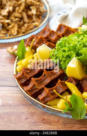 Cig kofte or raw meatballs on wood background. Traditional Turkish cuisine delicacies. Close-up. Stock Photo