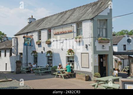 Tourists walkers people drinking sitting relaxing outside the Lake Road Inn pub in the town centre street in summer Keswick England UK United Kingdom Stock Photo
