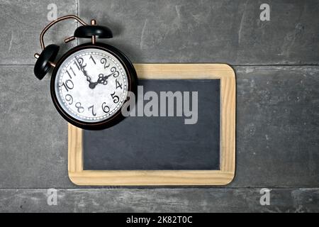 Retro alarm clock on blackboard with copy space. Stock Photo