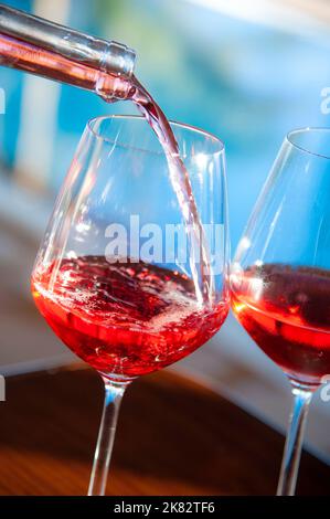 ROSÉ WINE Pouring fresh glasses of rosé wine in sunny sparkling sunlit alfresco luxury holiday vacation, summer infinity pool terrace resort Stock Photo