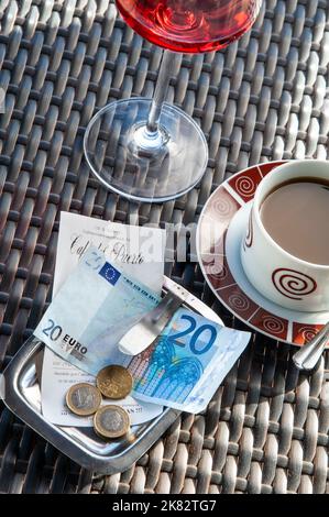 EUROS Restaurant bill receipt with 20€ note payment in Euros on sunny alfresco Spanish restaurant table with glass of rose wine and a cup of coffee Stock Photo