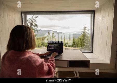 Woman works on laptop remotely in house on nature Stock Photo