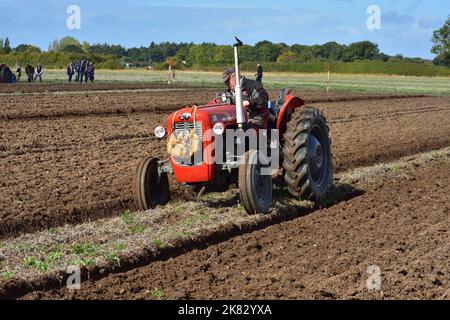 Red Massey Ferguson tractor ploughing open field with Lunchbox on the grill Stock Photo