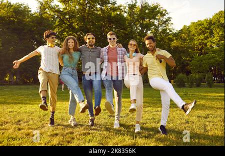 Diverse group of funny joyful young people having fun in sunny summer park all together Stock Photo