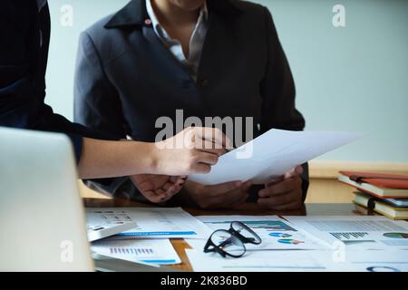 The company employee points to the document to calculate the budget and verify the correctness of the investment. Stock Photo