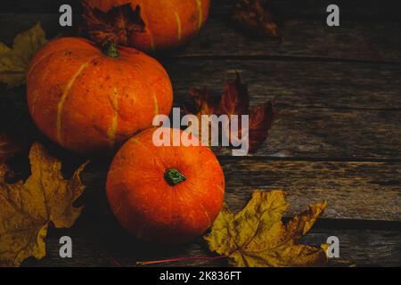 Pumpkins and fallen autumn foliage wooden background Stock Photo