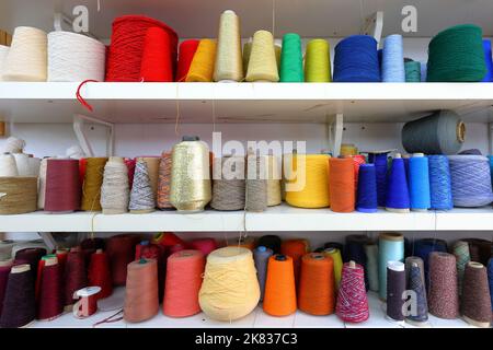 Cones and spools of colorful sewing thread organized by colour from red, orange, yellow, blue Stock Photo