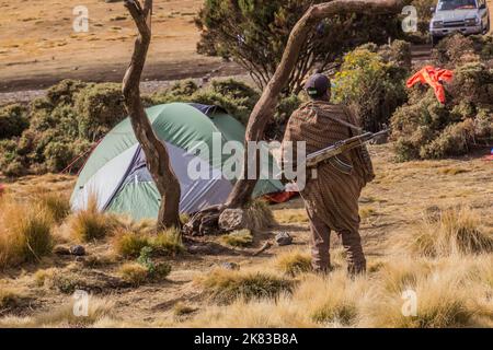 SIMIEN MOUNTAINS, ETHIOPIA - MARCH 16, 2019: Armed scout guarding tourists in Chenek camping  in Simien mountains, Ethiopia Stock Photo