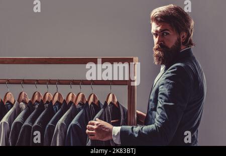 Elegant man's suits hanging in a row. Luxury mens classic suits on rack in elegant men's boutique Stock Photo