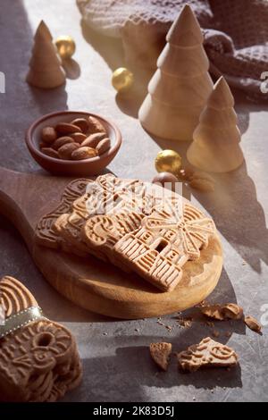 Speculoos or Spekulatius, Christmas biscuits, chocolate balls and almonds on a table with wooden Xmas tree toys. Traditional German sweets, cookies Stock Photo