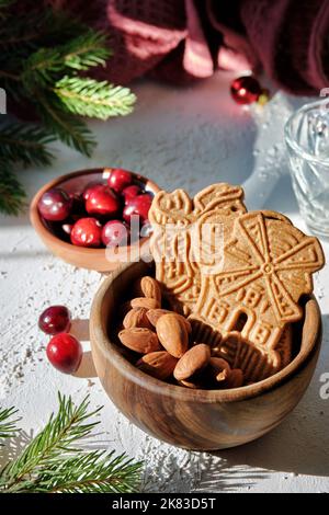 Speculoos or Spekulatius, Christmas biscuits, with cranberry berries, almonds on a table with kitchen towel and fir twigs. Traditional German sweets Stock Photo
