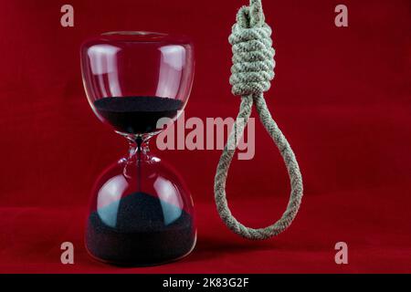 Hangmans rope noose and hourglass on a mottled red background Stock Photo
