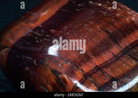 Brown and red tigers eye, dragons eye tumbled rock crystal smooth and shiny isolated on a black background surface copy space Stock Photo