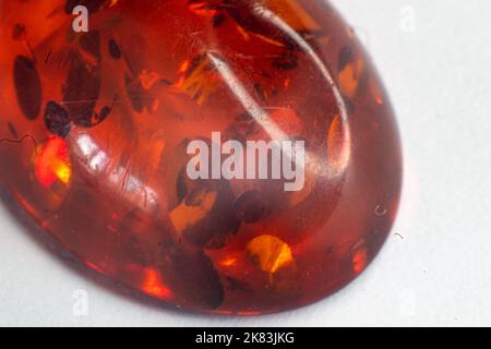 Macro heat treated deep orange amber cabochon with circular inclusions isolated on white surface Stock Photo