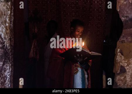 TIGRAY, ETHIOPIA - MARCH 22, 2019: Priest reading a Bible in Abuna Abraham Debre Tsion rock church in Tigray region, Ethiopia