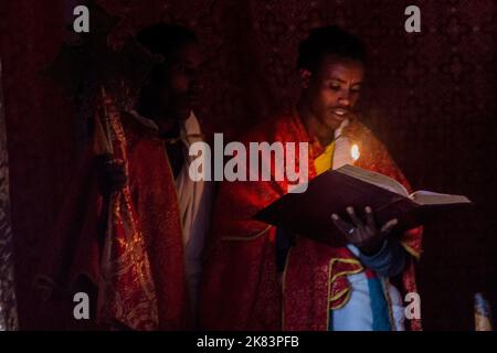 TIGRAY, ETHIOPIA - MARCH 22, 2019: Priest reading a Bible in Abuna Abraham Debre Tsion rock church in Tigray region, Ethiopia