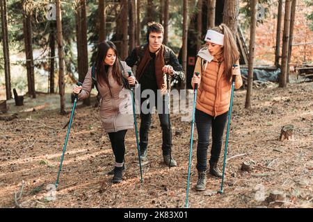 Friends climbing up the hill together, laughing and having fun. Autumn colors Stock Photo