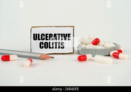 Medical concept. On a white background, medical capsules, a pencil and a cardboard plate with the inscription - Ulcerative colitis Stock Photo