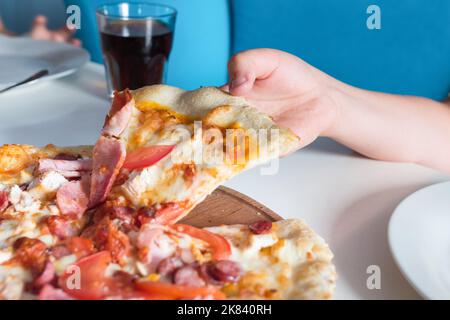 Children's hand with pizza, closeup on the table Stock Photo