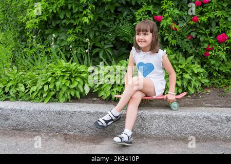 Smiling girl sitting on the blackboard, outdoors Stock Photo
