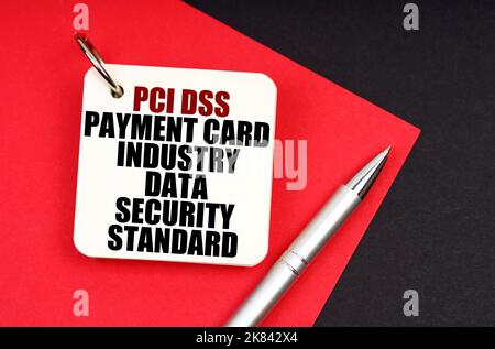 Industry and business concept. On a black and red background lies a pen and a notebook with the inscription - Payment Card Industry Data Security Stan Stock Photo